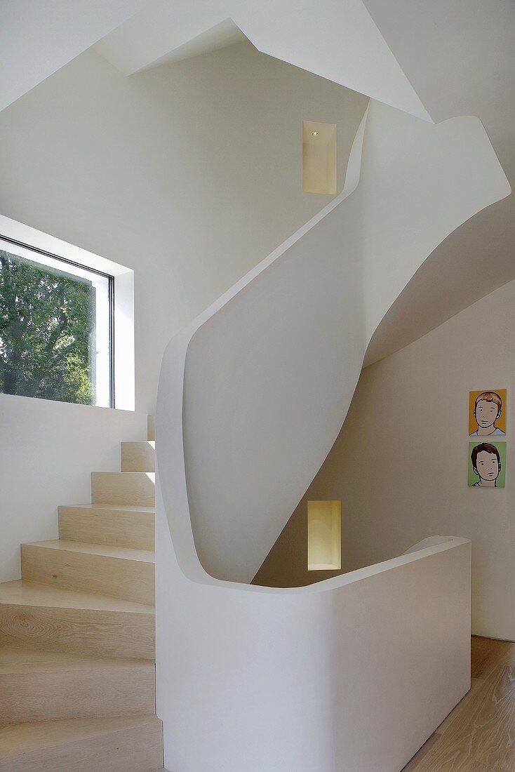 Gewendelter Treppenlauf mit Holzstufen und gemauertem Geländer im Designerstil