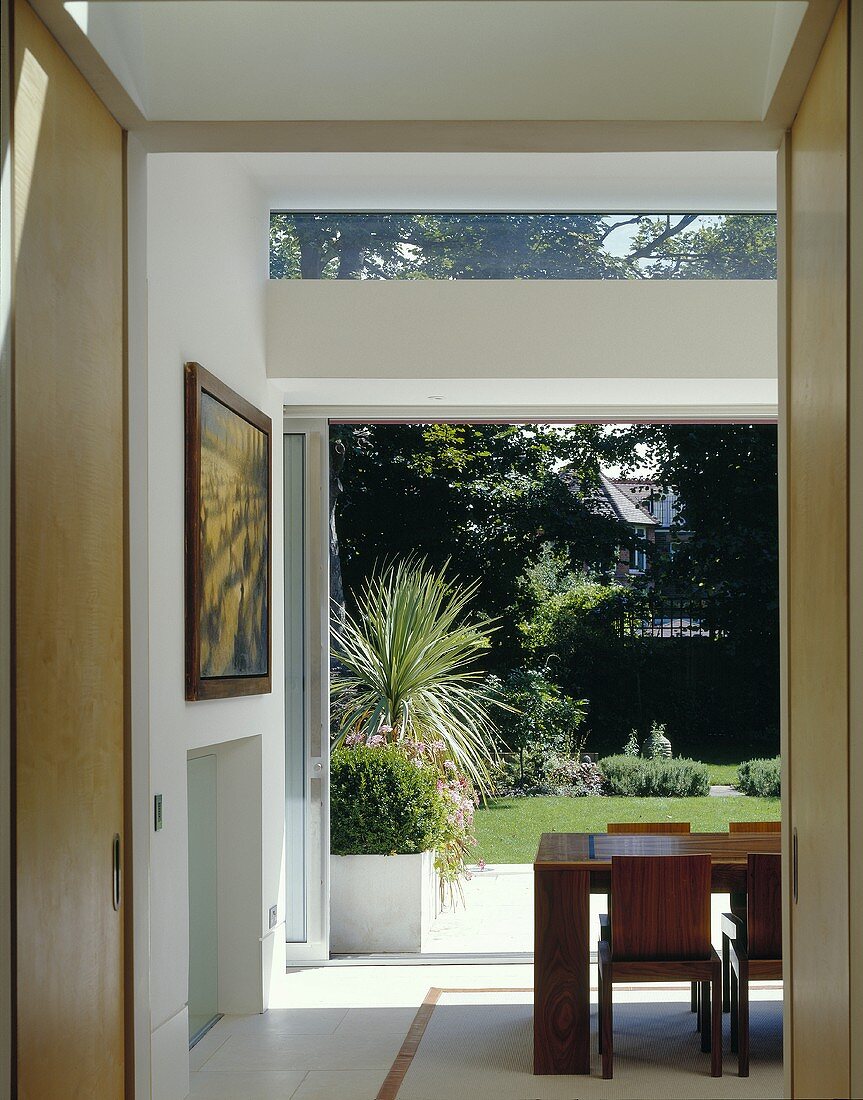 Blick durch offenen Durchgang einer modernen Wohnung auf offene Terrasse in Garten