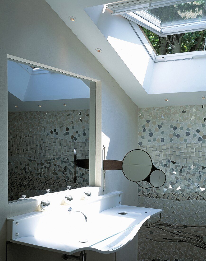 Geschwungenes Designerwaschbecken mit in Wand eingelassenem Spiegel und geöffnetem Dachflächenfenster
