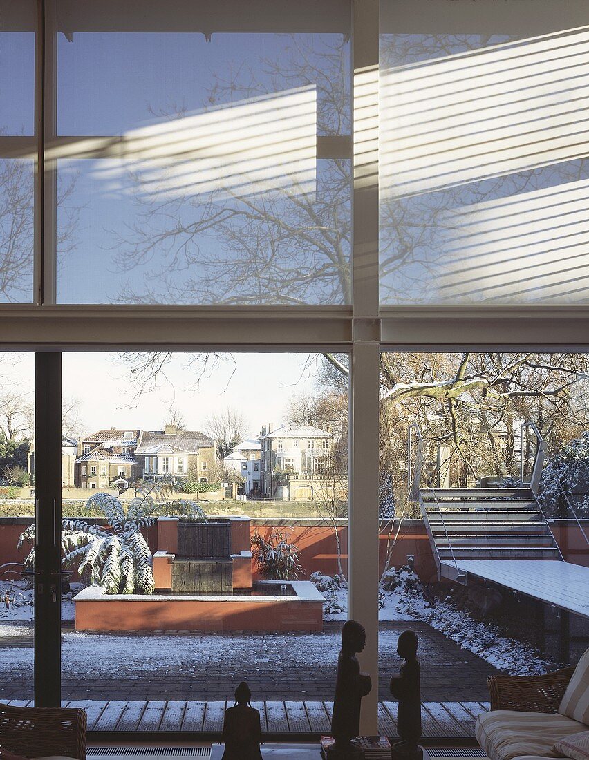 Facade of steel and glass in a modern living room with a view of snow covered garden
