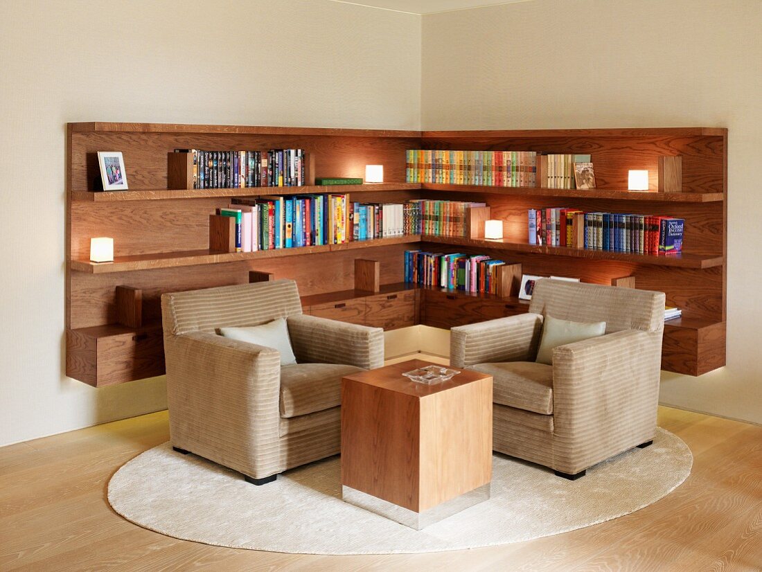 Classic living room corner with modern side table in front of chairs and built in wood bookshelves opposite