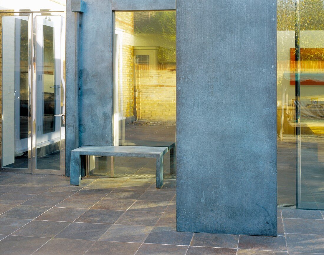 Vorraum mit Fliesenboden und Raumteiler aus Stahl vor Bank an Fensterfront