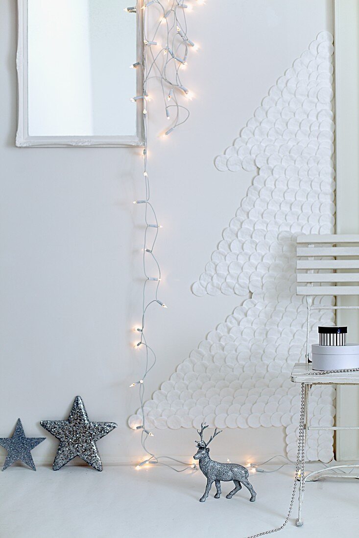 A Christmas tree made of cotton wool pads a wall with a chain of fairy lights and Christmas decorations