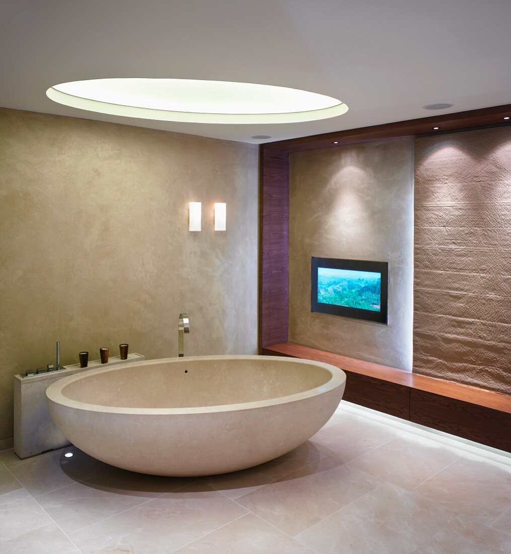 Ovale freistehende Badewanne mit Designerarmatur unter rundem Oberlicht
