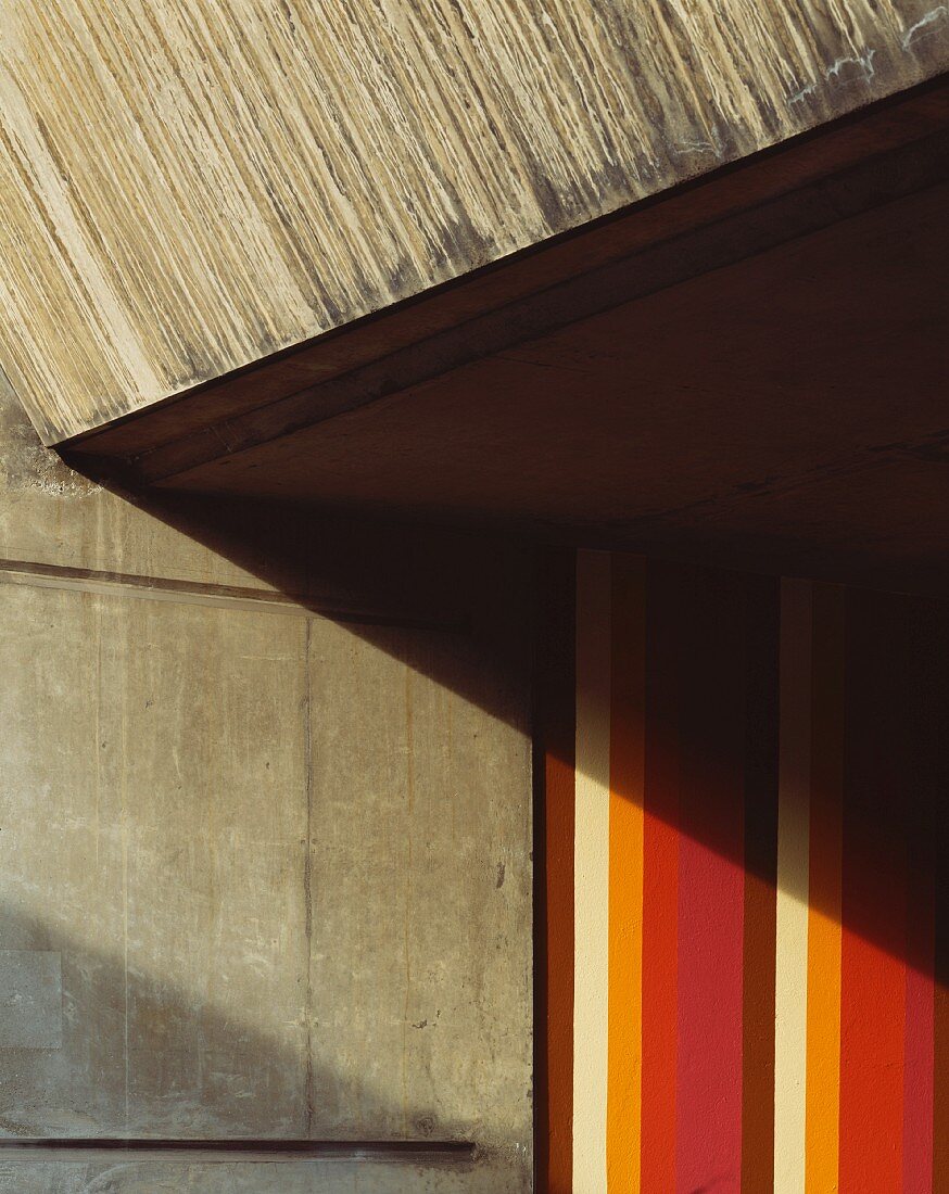 Ausschnitt einer Betonfassade eines Hauses und bunte Farbstreifen