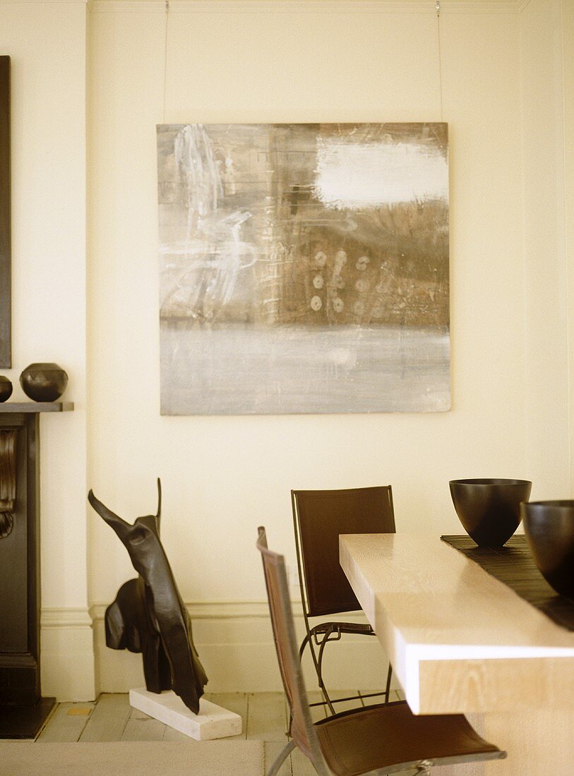 Cream dining room with brown chairs and artwork.