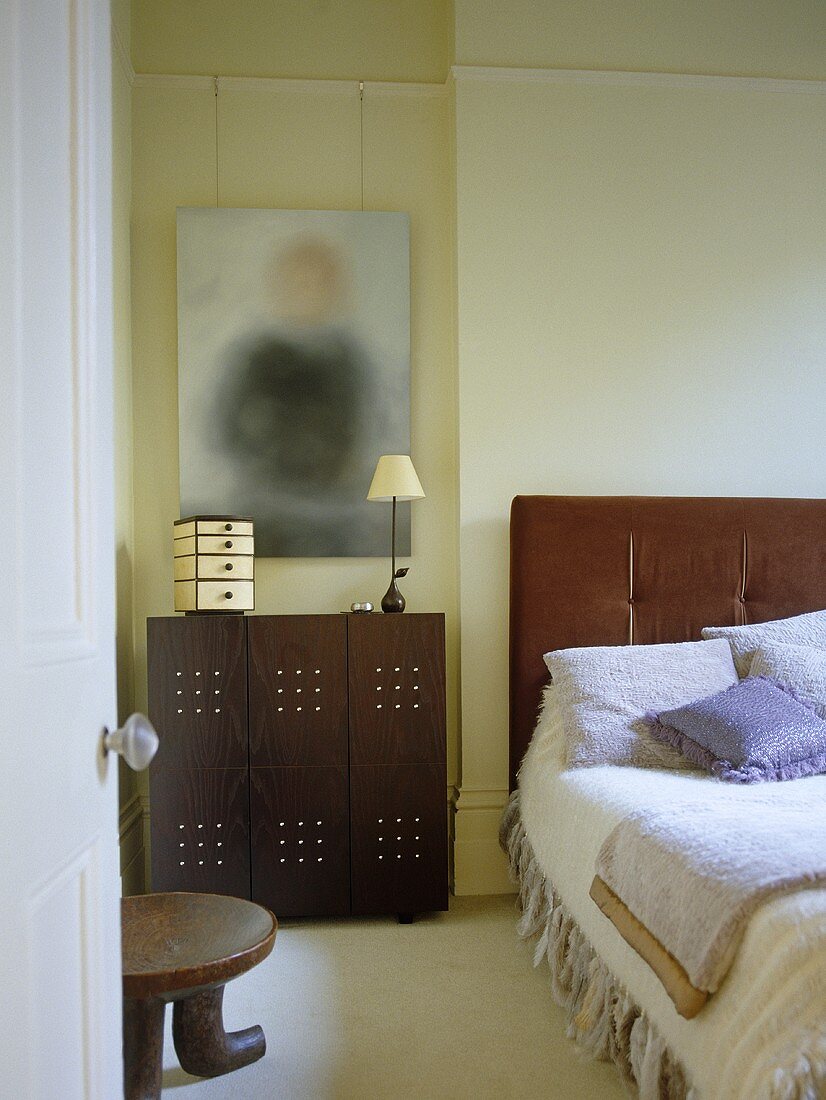 Blick durch offene Tür in Schlafzimmer auf modernen Schrank als Nachttisch und Bett.