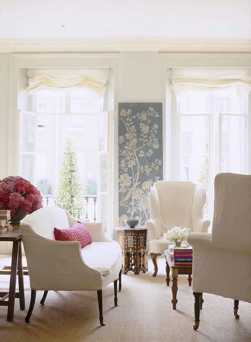 Traditionelles Wohnzimmer mit weisser Sofagarnitur vor französischen Fenstern