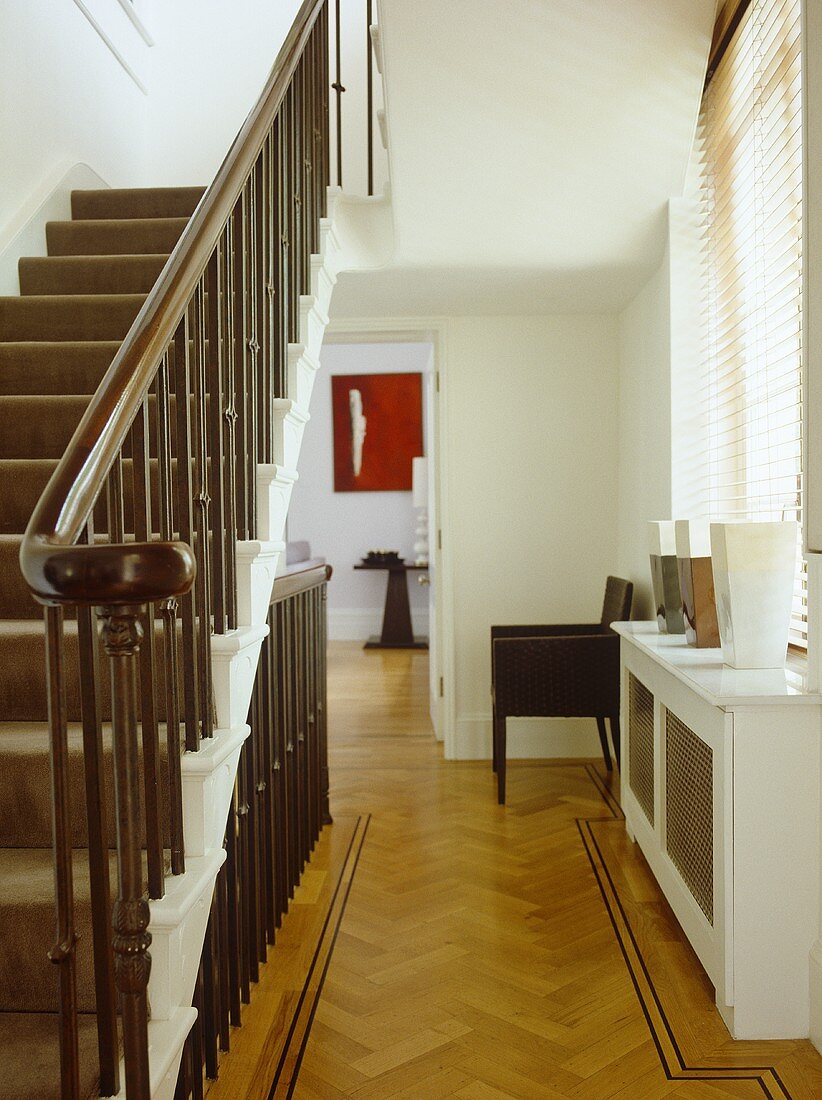Treppenhaus mit Holzgeländer an Treppe und Blick durch offene Tür