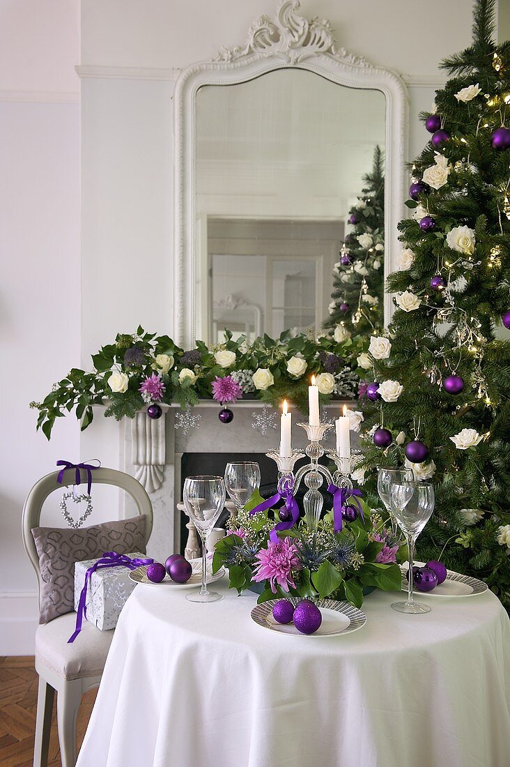 A festively laid table in front of a decorated mantelpiece with a mirror