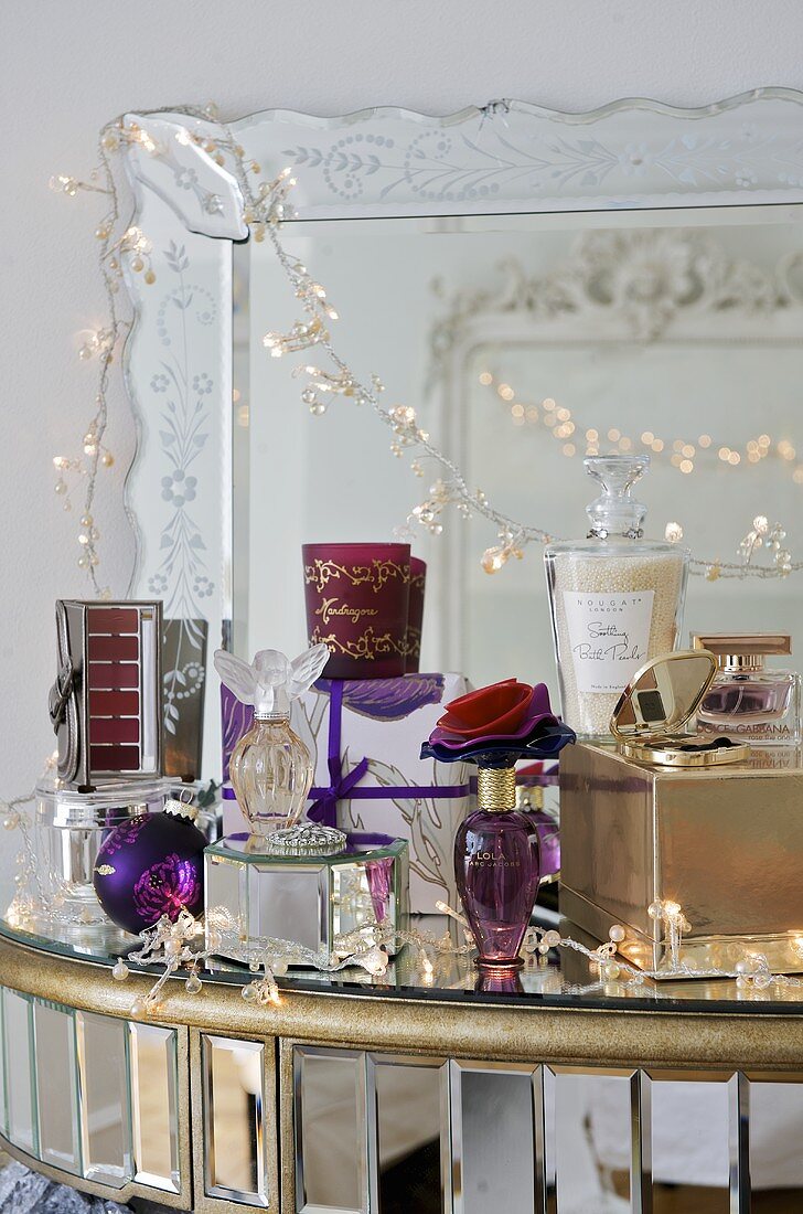 Parfumflakons auf Ablage vor Spiegel mit Lichterkette