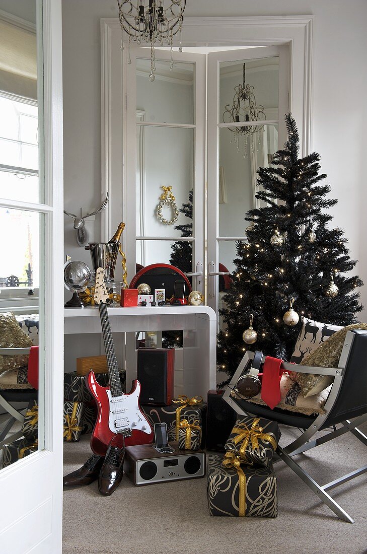 A musical instrument and presents in front of a wall table and a Christmas tree