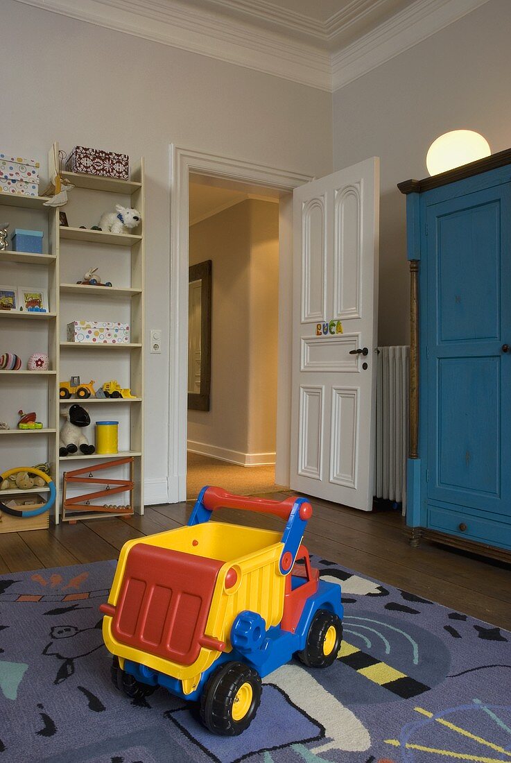 Child's room with a toy on a carpet and open door with a view of a hallway