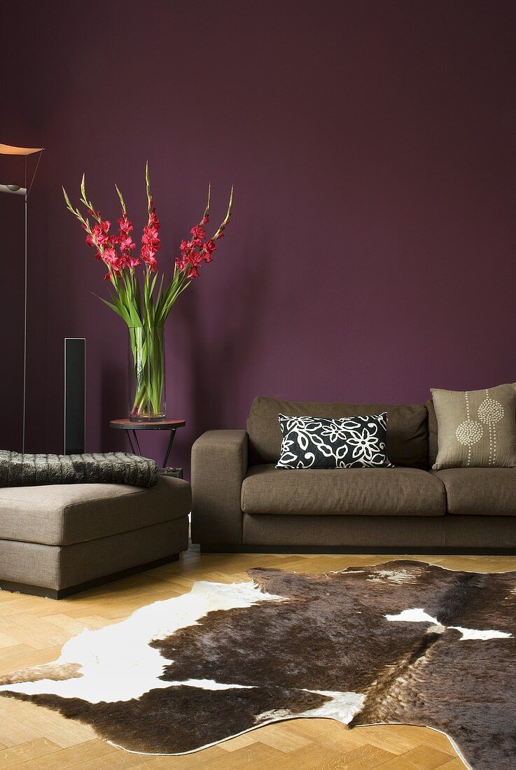 Animal hide on wooden floor and gray sectional in front of a purple wall