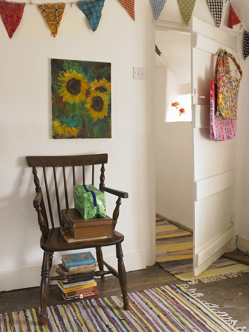 A rustic wooden chair on a striped rug and an open, white-painted door