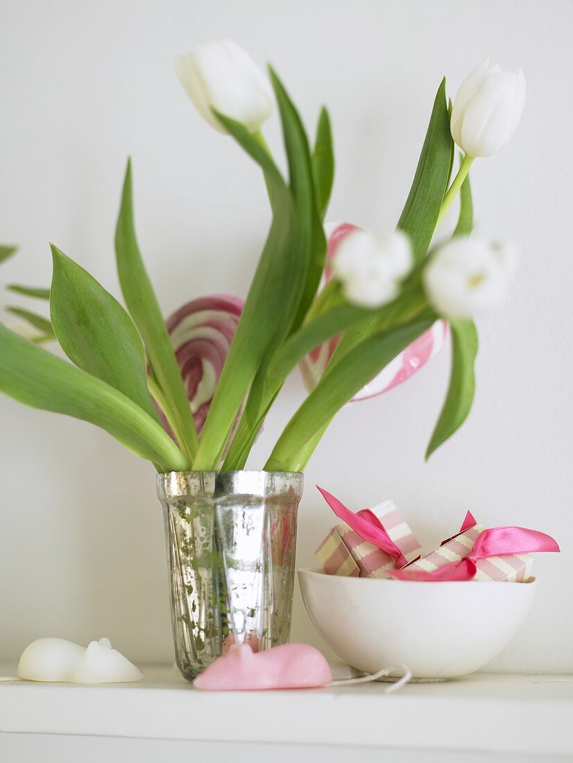 White tulips in a sliver vase next to a porcelain bowl