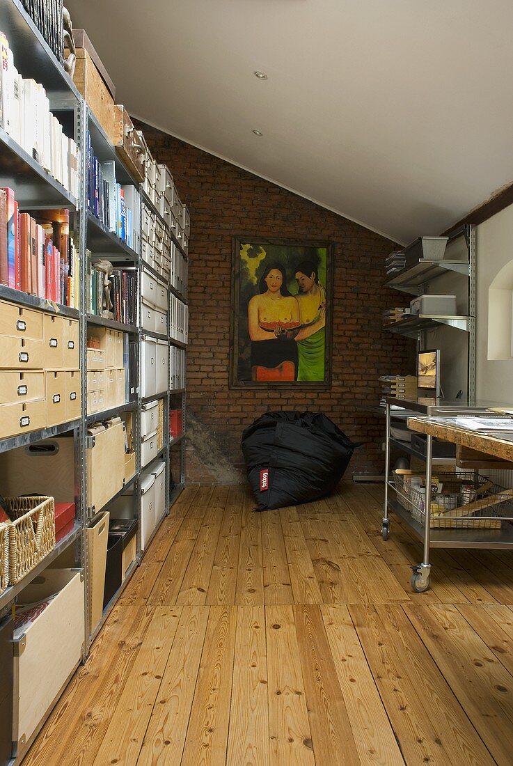 Modern office area with pouf in front of a brick wall and metal shelves