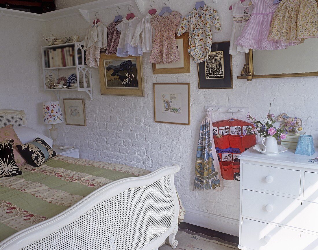 Ländliches Schlafzimmer mit Kinderkleidern an Wand hängend