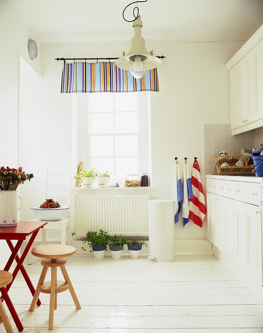 A white kitchen in a country house with wooden stools