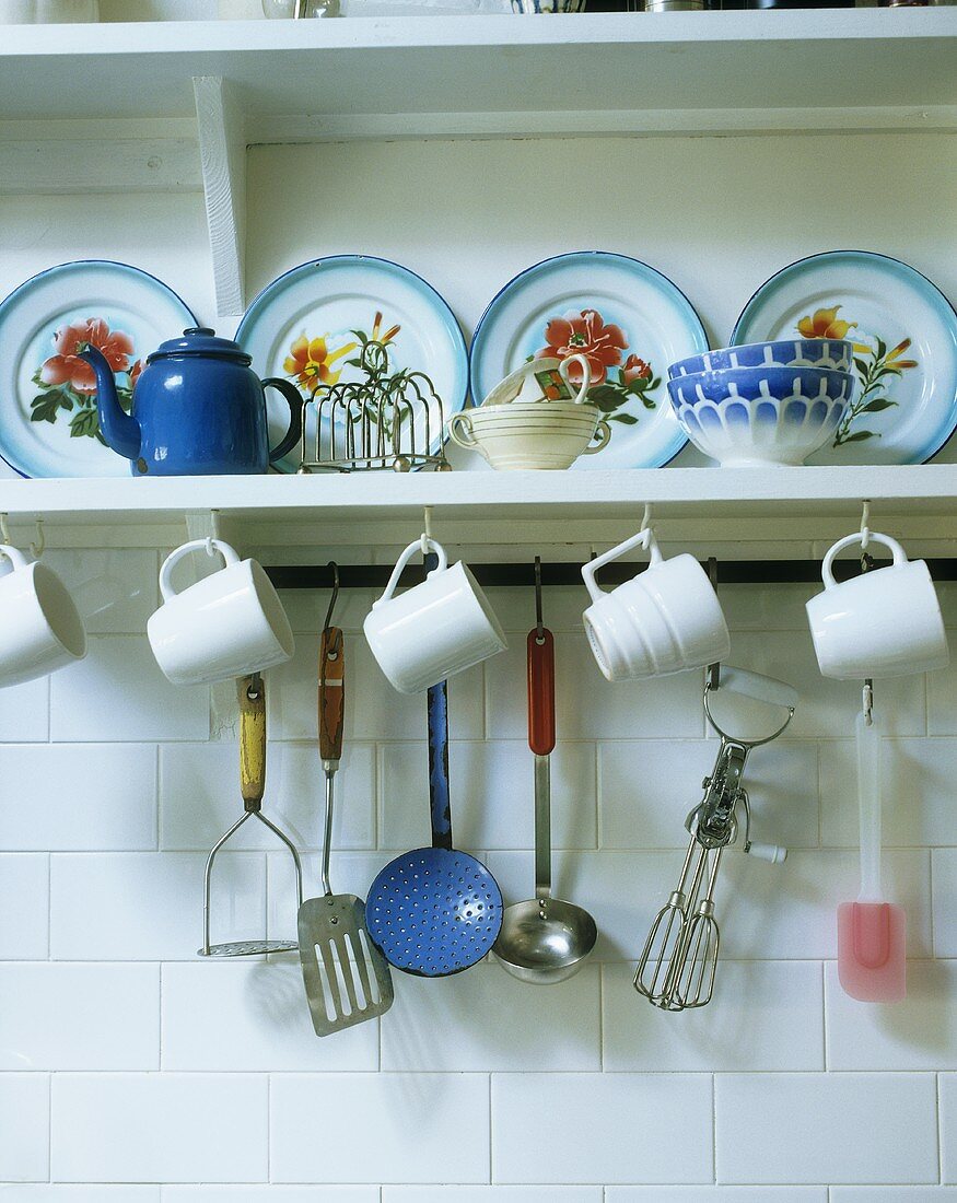 Mugs and kitchen utensils hanging on a plate rack