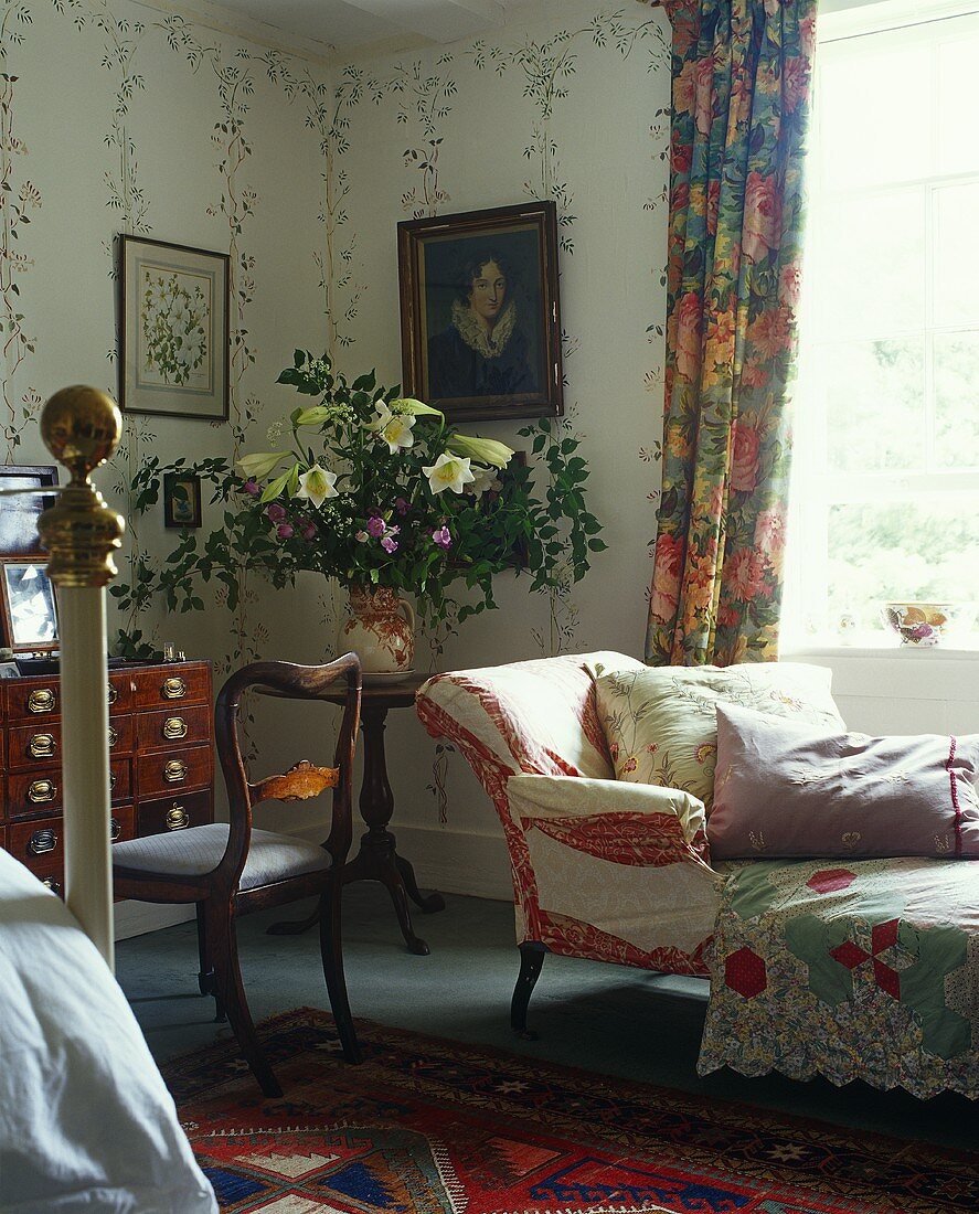 A lounger in front of a window and an antique chair in a traditional room
