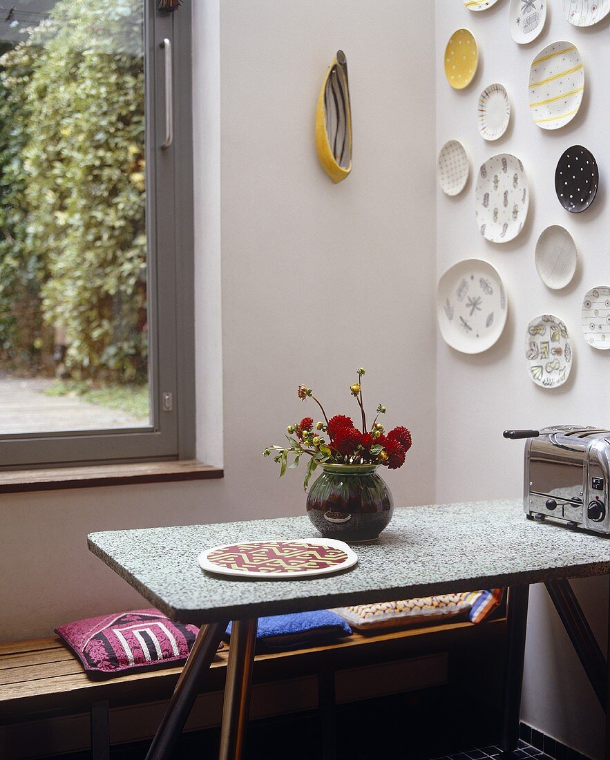 Küchenecke mit Wandtellern über Tisch und Bank
