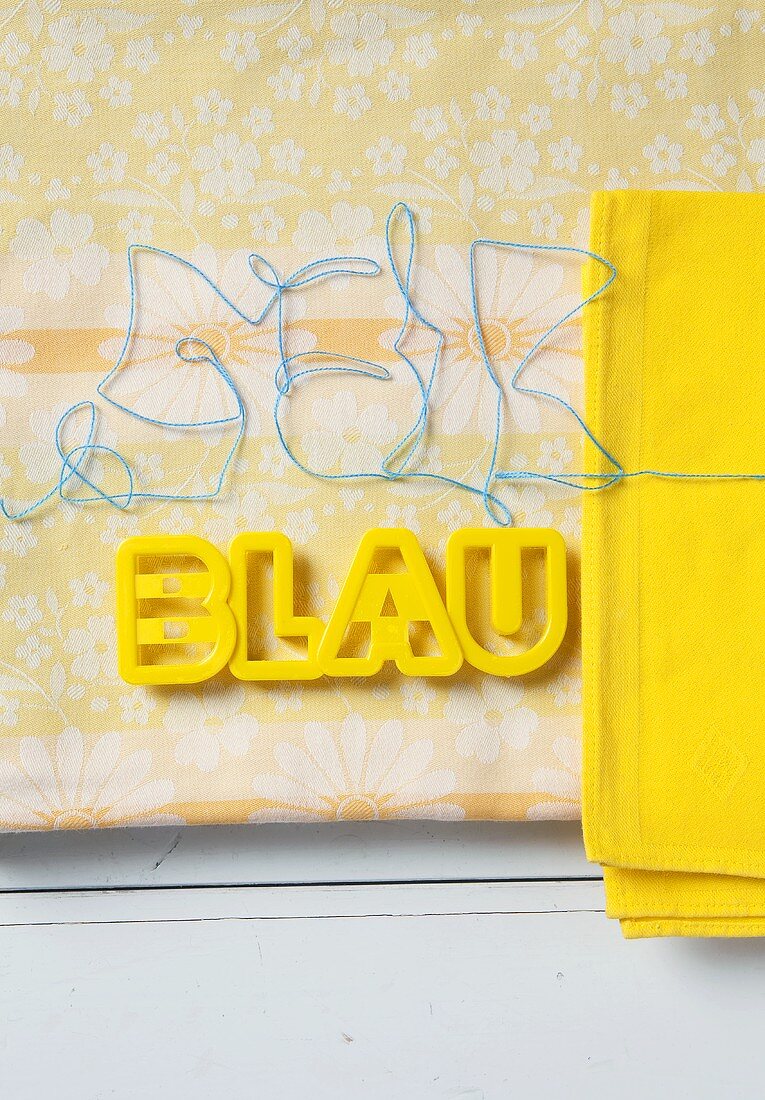 Yellow plastic letter on a piece of patterned fabric