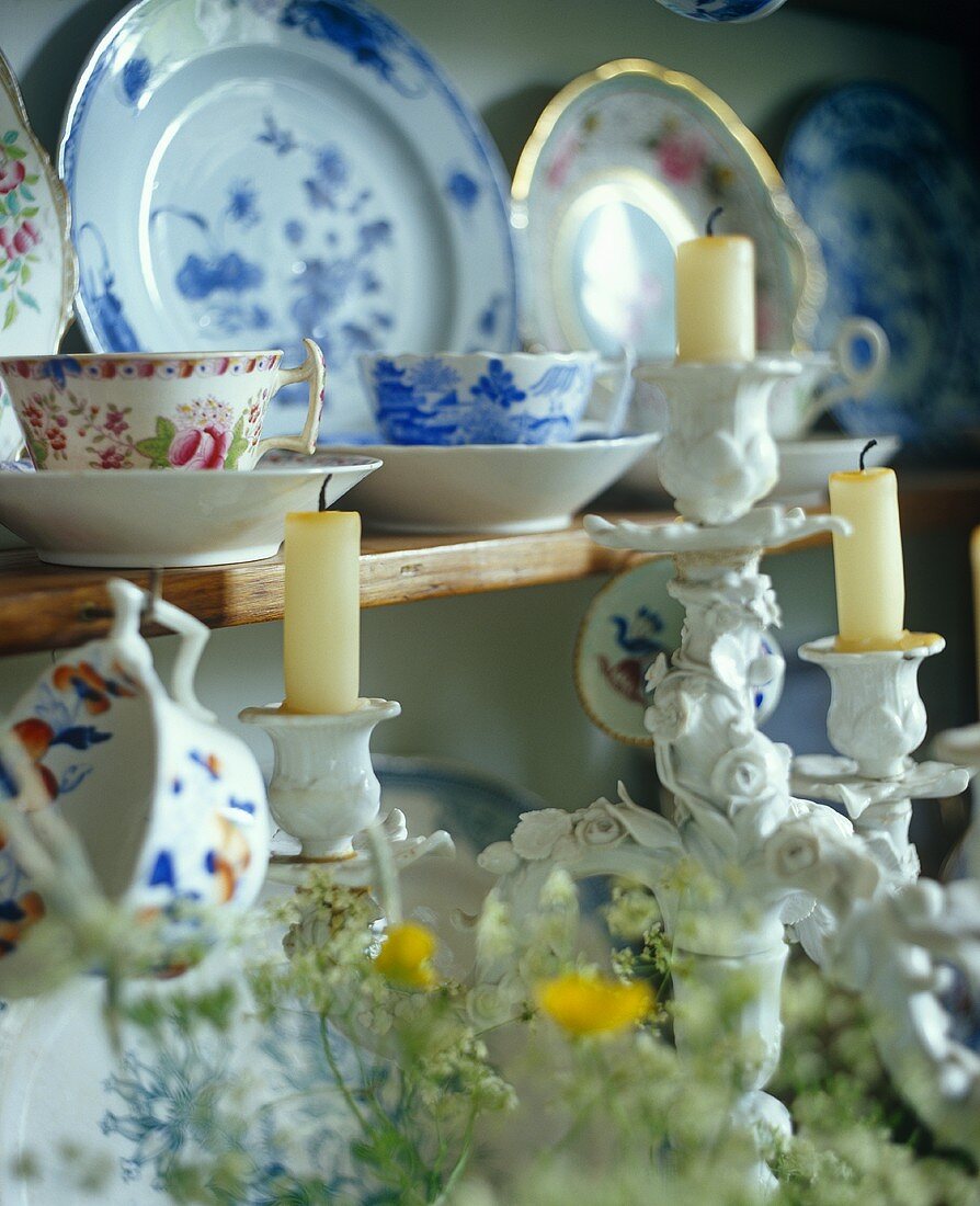 Porcelain candlesticks in front of crockery on a shelf
