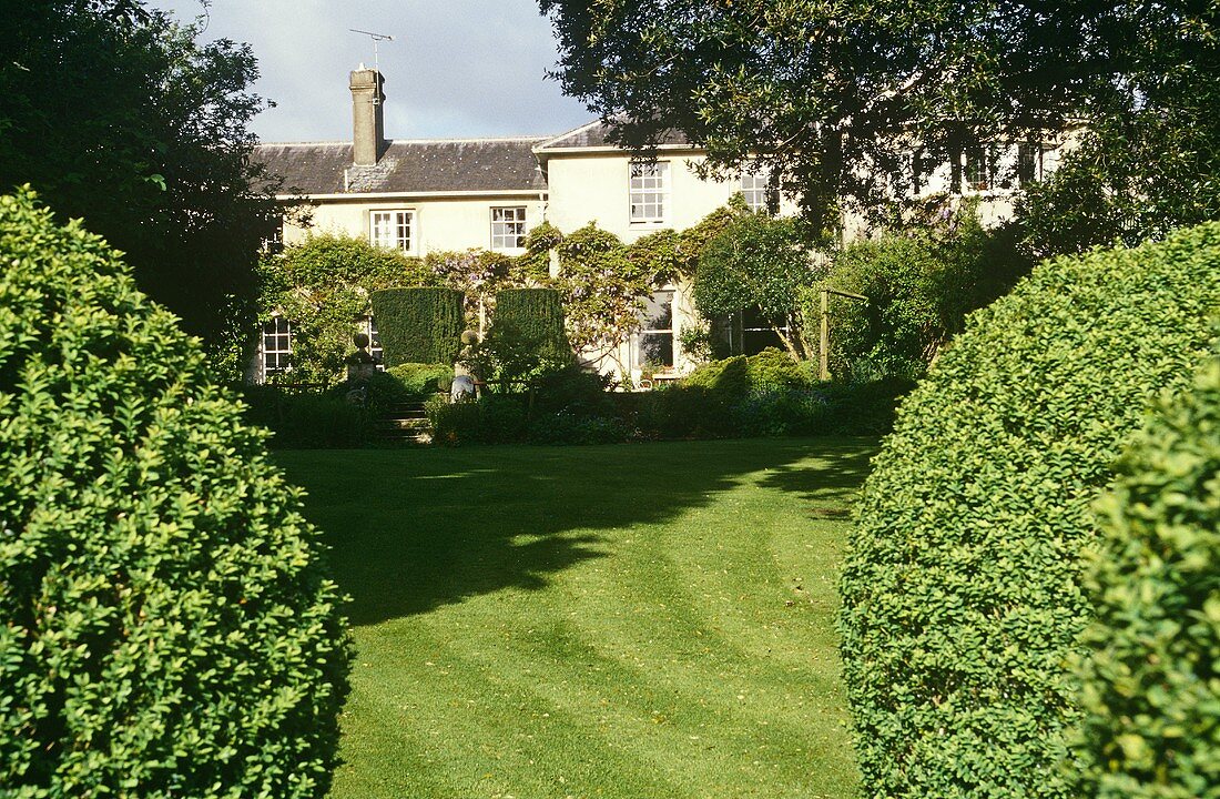 Garten mit Buchsbäumen und englischem Landhaus