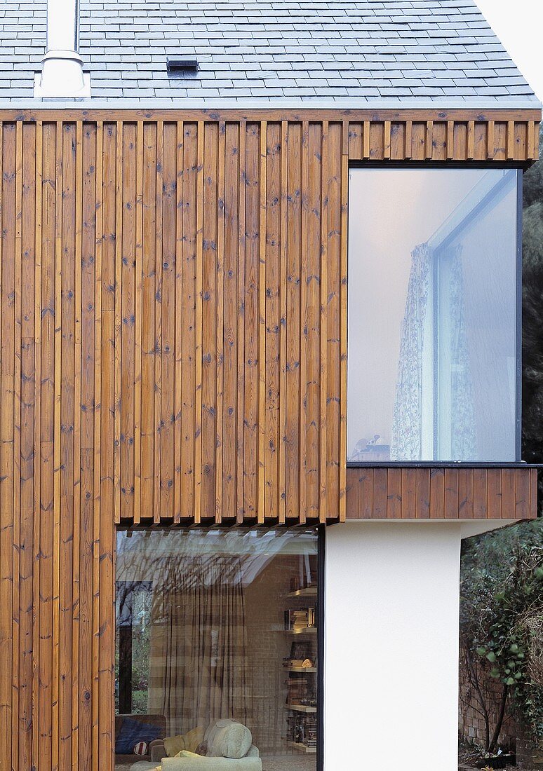 Vertikale Holzverkleidung am Neubauhaus mit raumhohem Fenster