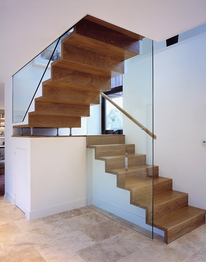 A wooden stairway and glass side walls in an open stairwell