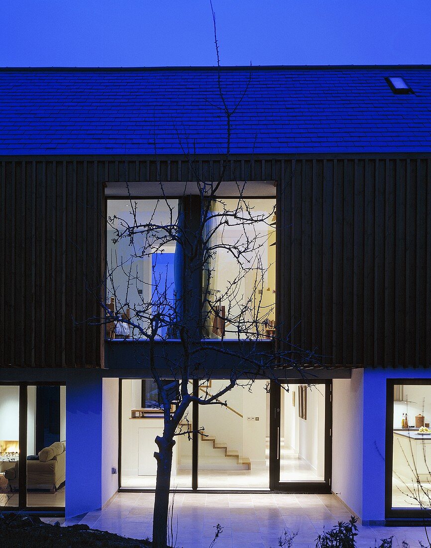 Neubauhaus mit beleuchtetem Eingangsbereich in Nachtstimmung