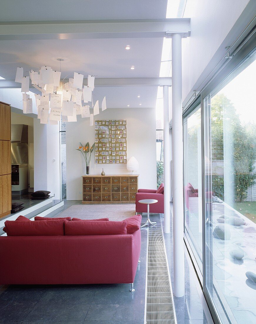 A pink sofa and a designer lamp in a living room with a window bank