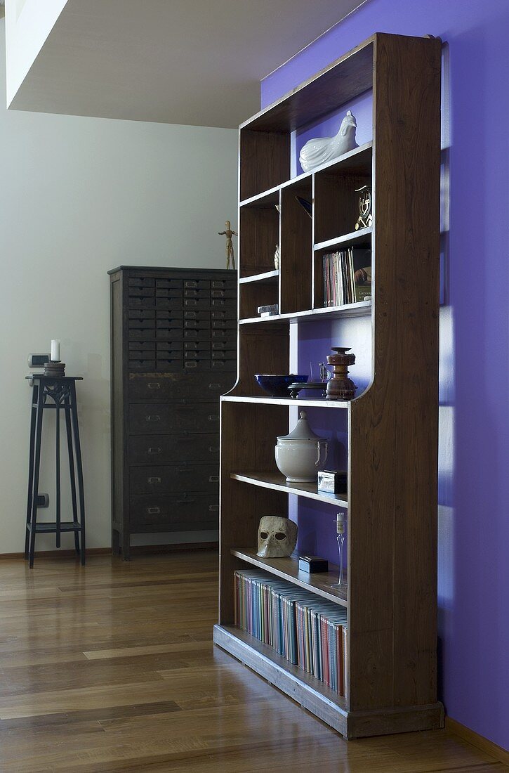 Antikes Bücherregal vor violetter Wand