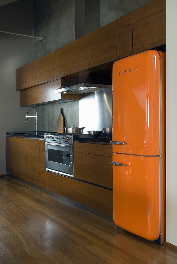 An open-plan kitchen with an orange 1950s style fridge