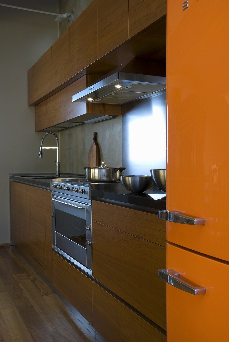A kitchen with wooden cupboards and an orange fridge