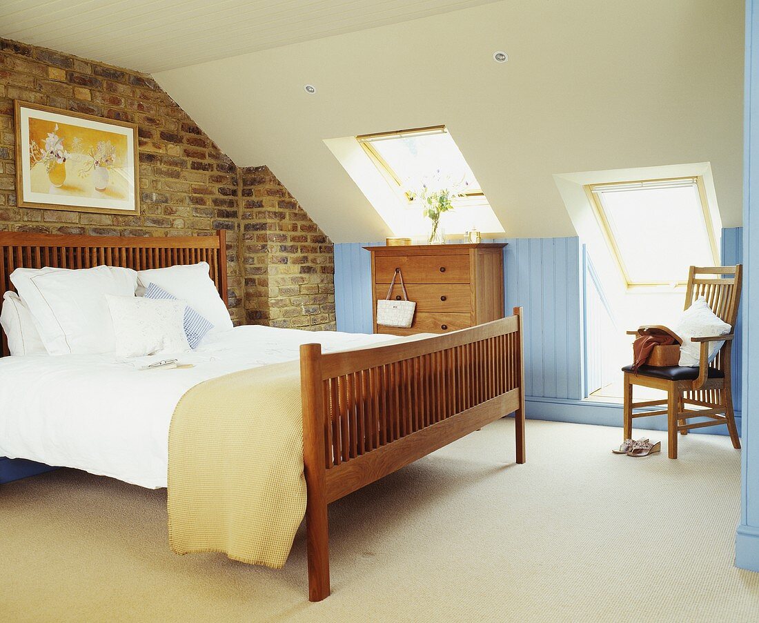 Zeitgenössisches Schlafzimmer mit Sichtmauerwerk und Doppelbett mit Holzgestell im Dachzimmer mit Dachfenstern