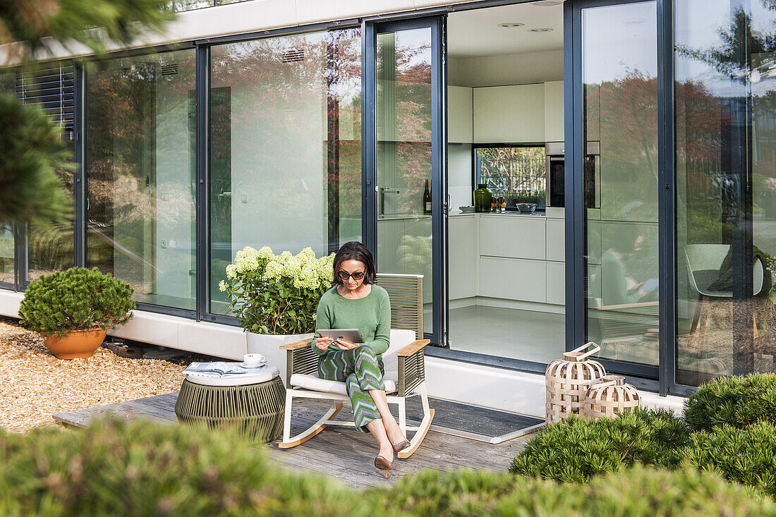 Frau sitzt auf einer Terasse und liest im iPad, coodo moderne Art zu Wohnen, moderne Architektur in Hamburg, Hamburg, Norddeutschland, Deutschland