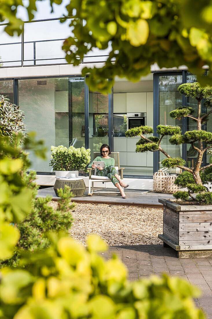 woman sitting on a terrace with an iPad,modern architecture n in Hamburg,north Germany,Germany