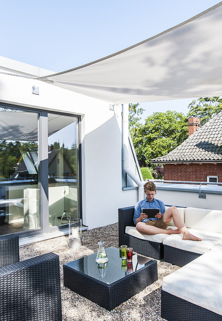 Junge mit iPad auf der Dachterrasse eines modernen Einfamilienhaus in Hamburg, Norddeutschland, Deutschland