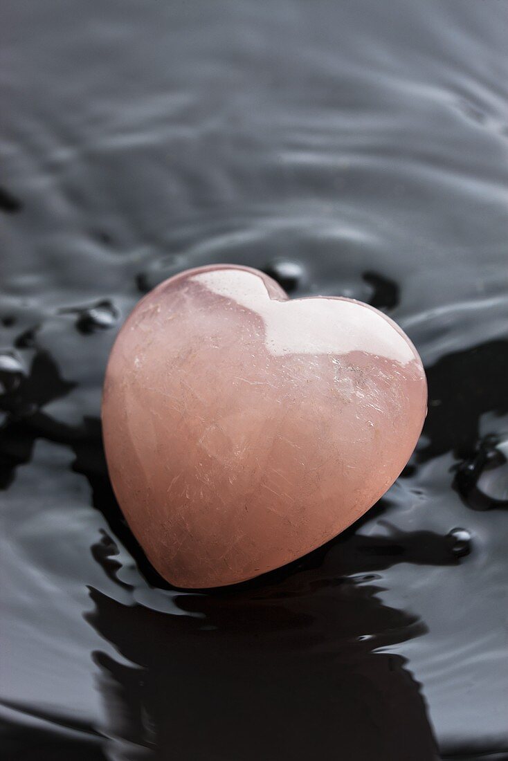 Heart made of rose quartz in a black bowl with water