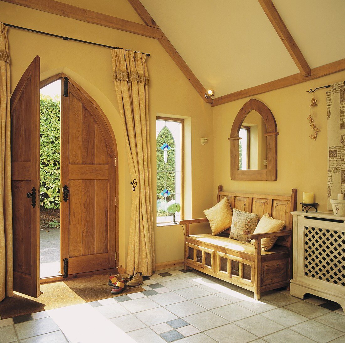Eingangsraum eines Landhauses mit gothischer Flügel-Holztür und einem gothischen Spiegel mit Holzrahmen an der Wand