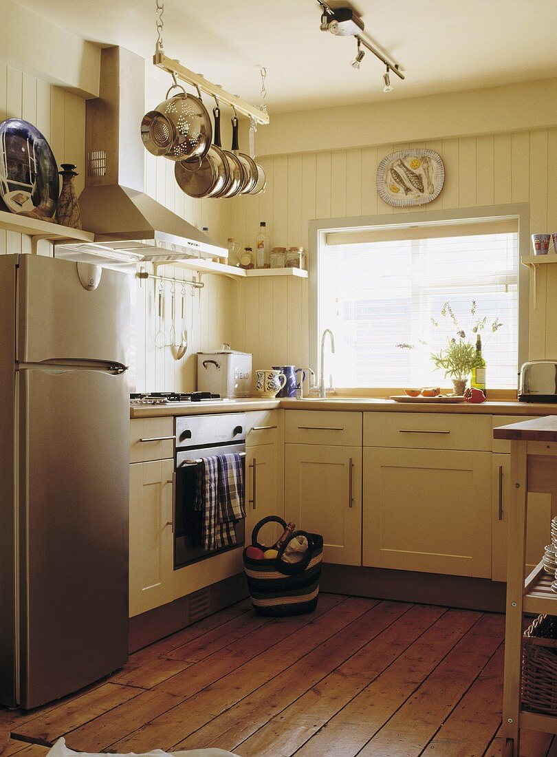 Cremefarbene Küche in einem Ferienhaus mit Holzdielen und einem großen Edelstahl-Kühlschrank mit Gefrierfach