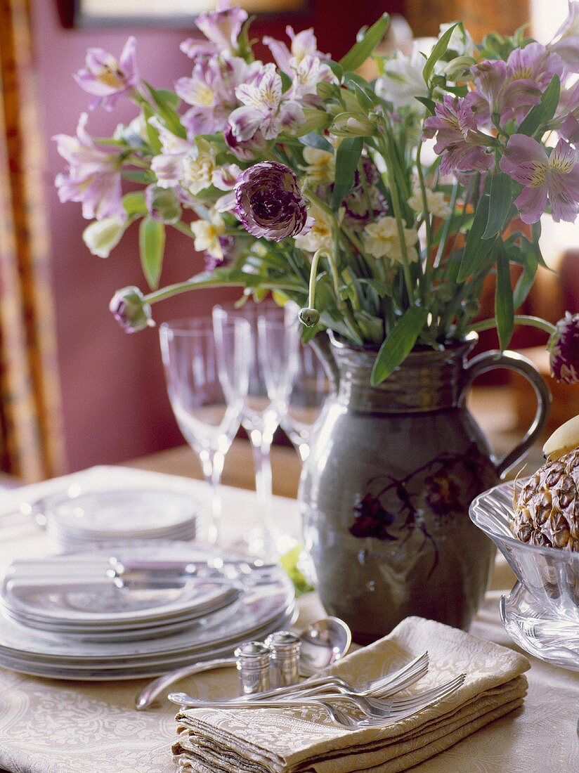 Esstisch mit Keramikkrug und frischen Blumen darin