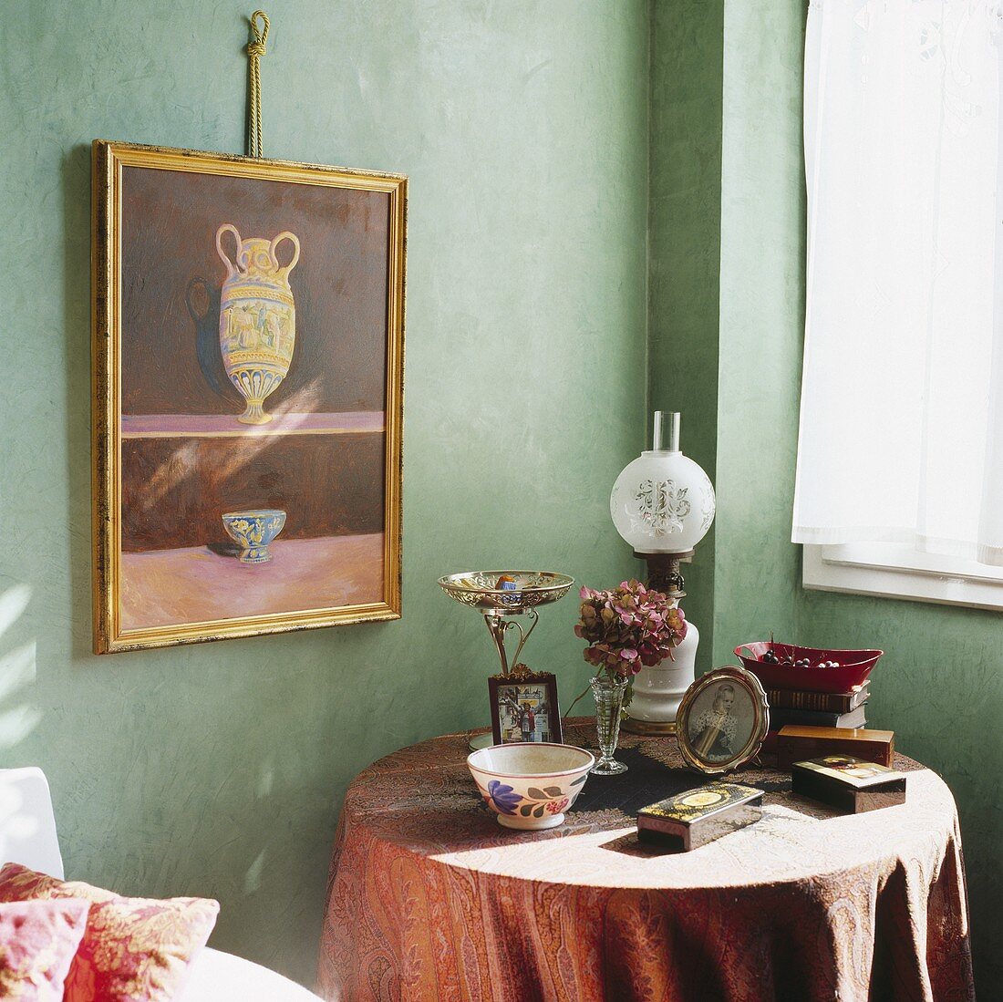 Ein Bild hängt über einem kleinen Tisch mit viktorianischer Öllampe, Fotos und Schälchen