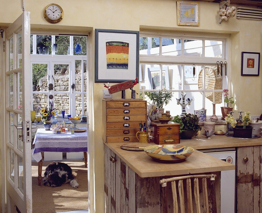Rustikale Holzarbeitsplatte und Schränke in einer Landhaus-Küche mit Glastür zum Esszimmer im Wintergarten