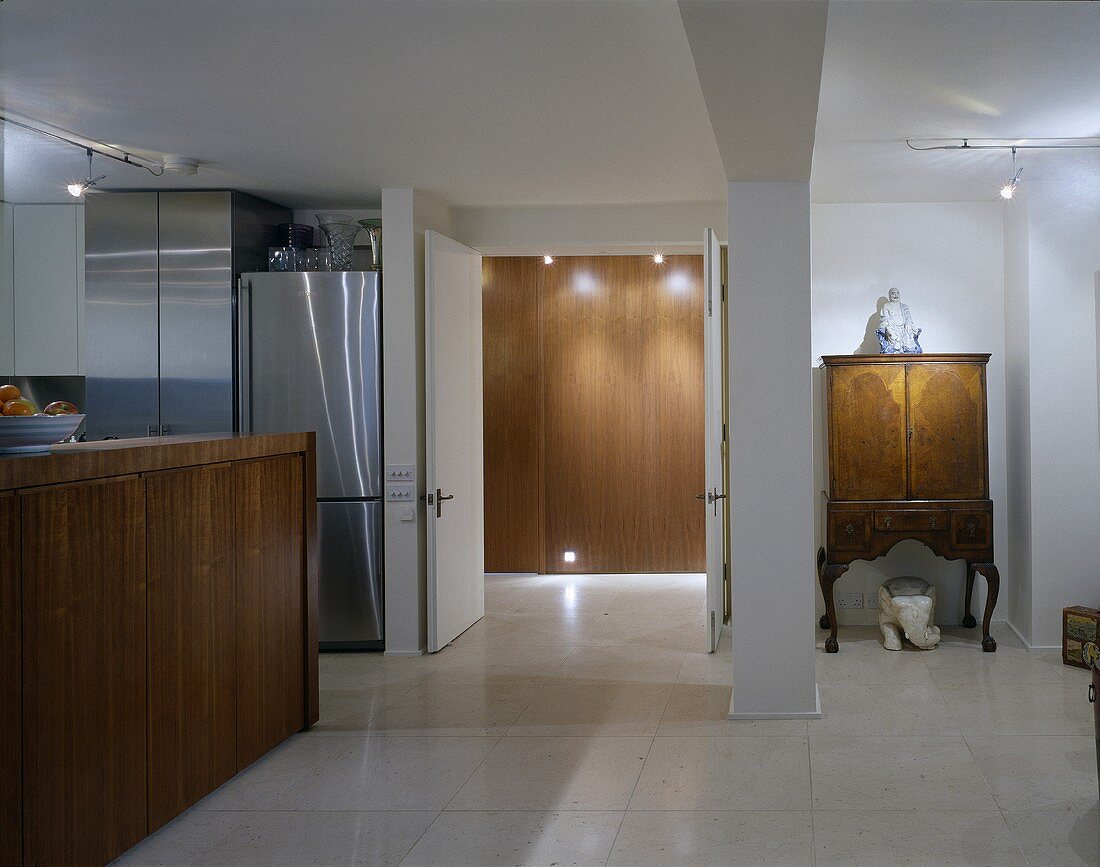 Offener moderner Wohnraum mit Küchentheke und antikem Schrank neben offener Tür