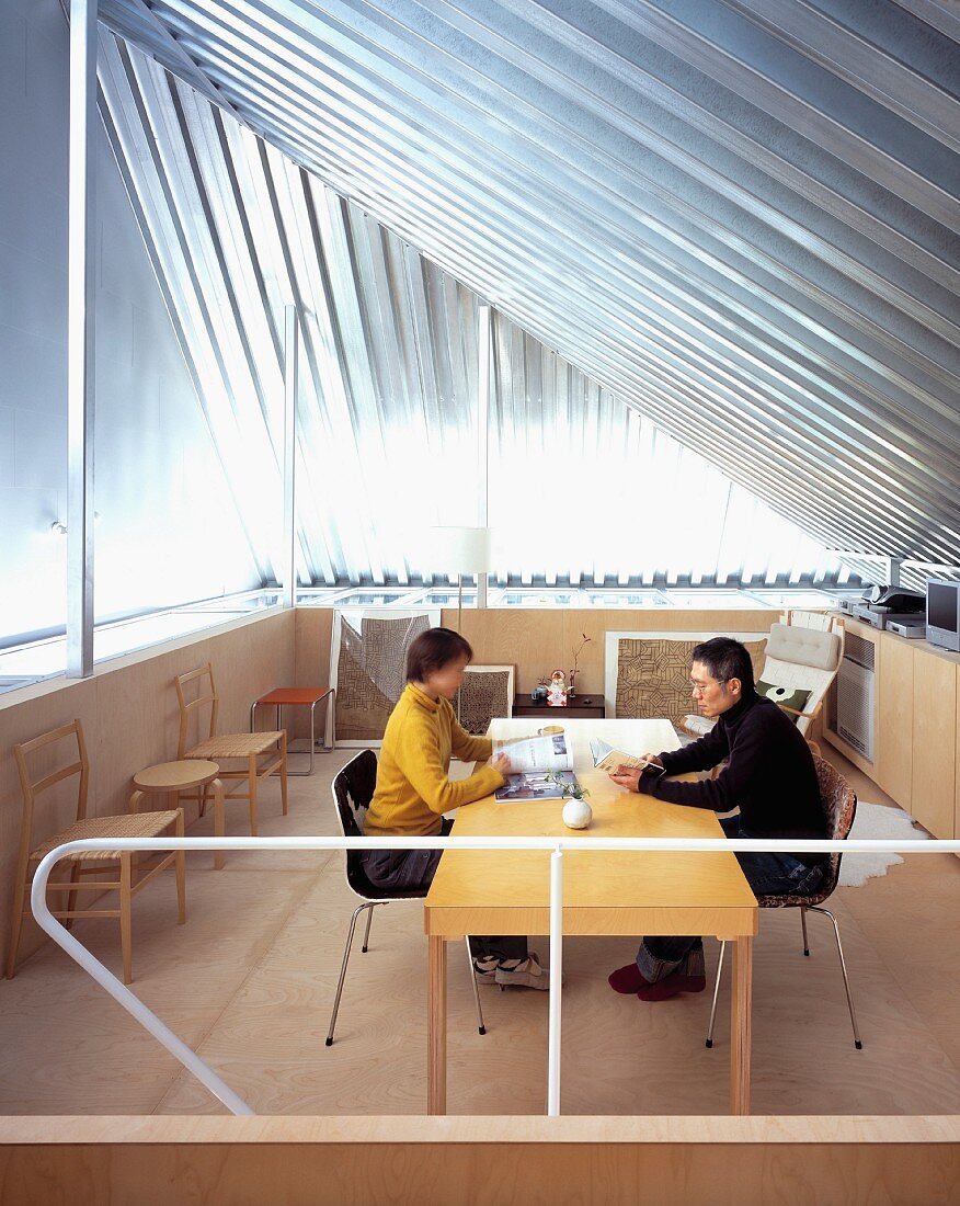 Paar am Tisch sitzend unter offenem Dachraum mit Metallverkleidung