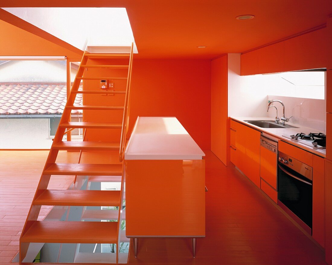 Treppe trennt offene rotgetönte Küche mit Theke vom Wohnraum
