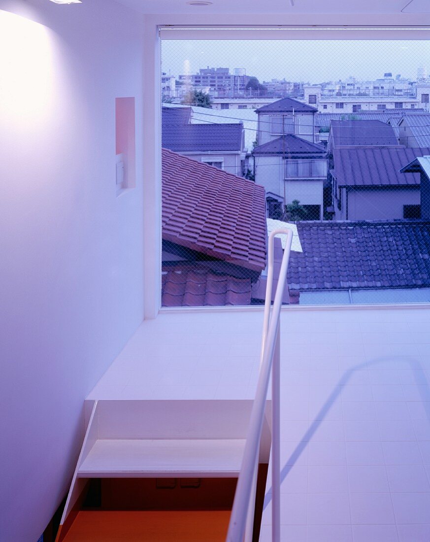 A stairwell and landing with a window and a view over the town